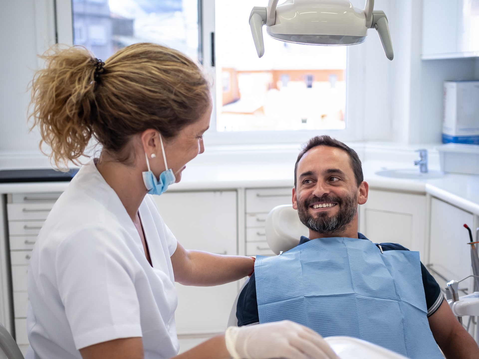 A patient in a dental chair smiles at a dentist during the appointment